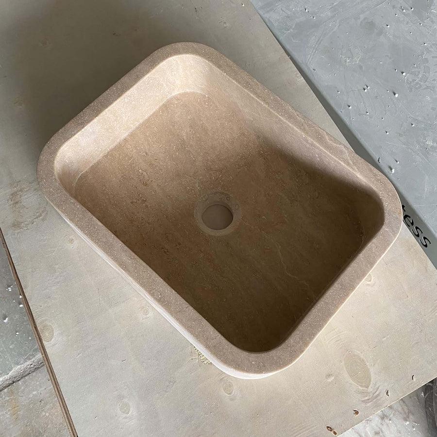 Beige travertine rounded floating sink styled in a designer powder room