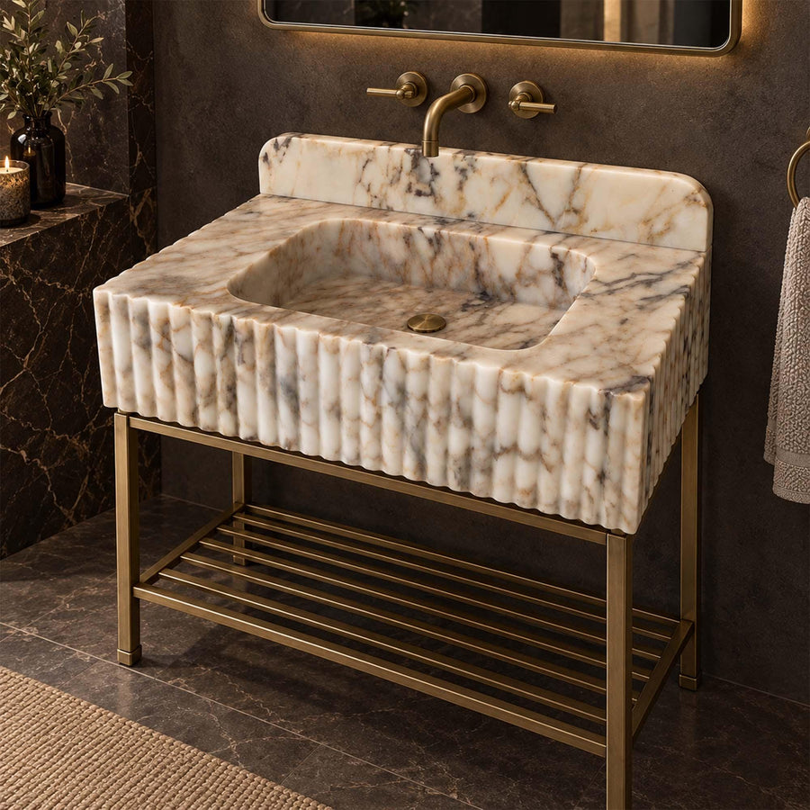 Calacatta Gold fluted marble sink with rounded backsplash on a custom brass vanity stand