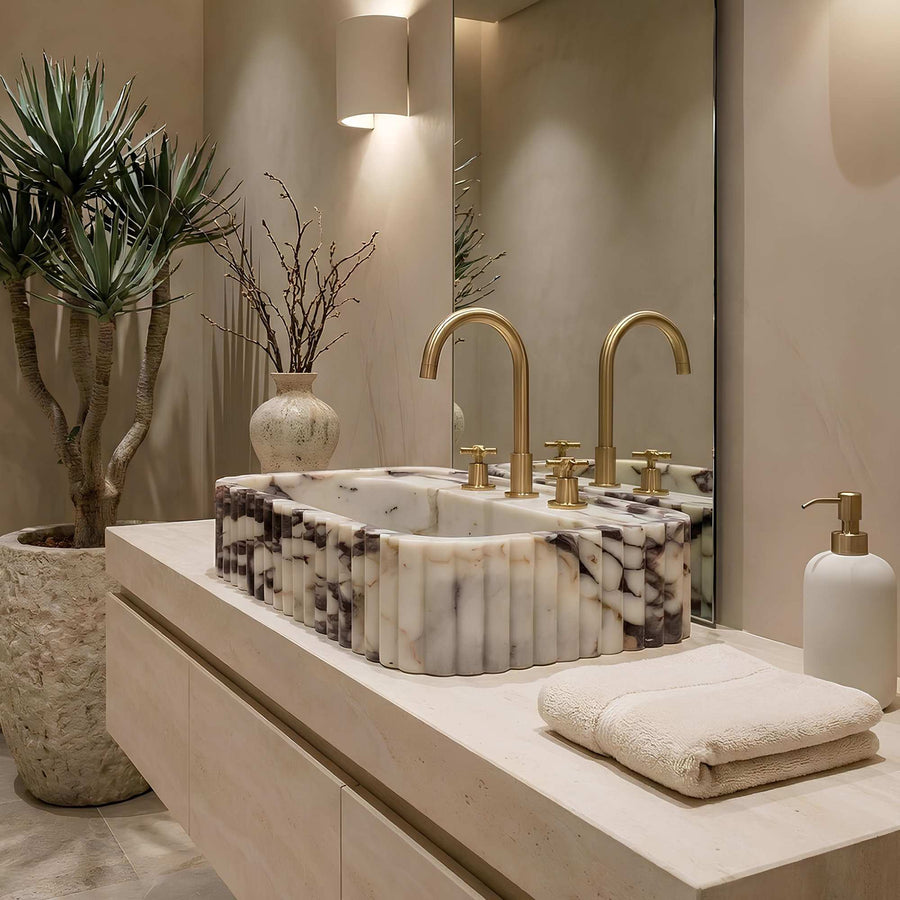Bathroom vanity with marble sink, gold fixtures, and decorative elements.