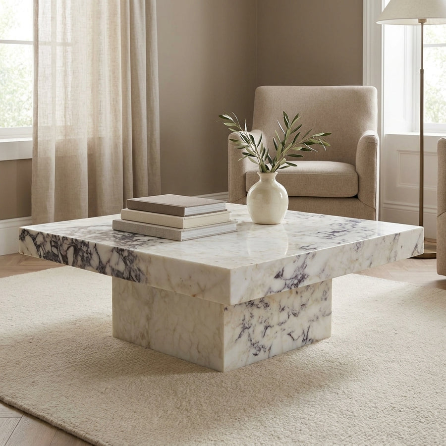 Marble coffee table in a living room setting with a vase and books on top.