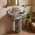 Marble pedestal sink with bridge faucet on terracotta floor