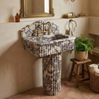 Marble pedestal sink with bridge faucet on terracotta floor
