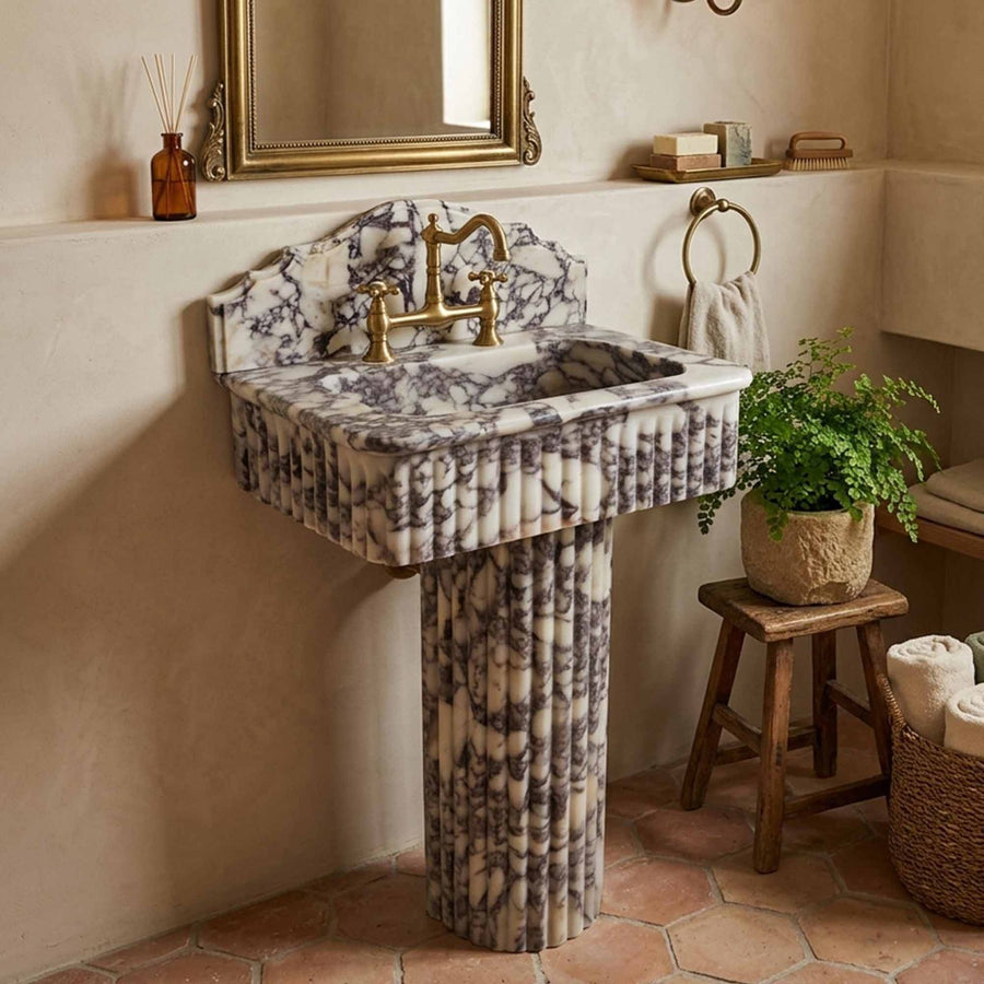 Marble pedestal sink with bridge faucet on terracotta floor