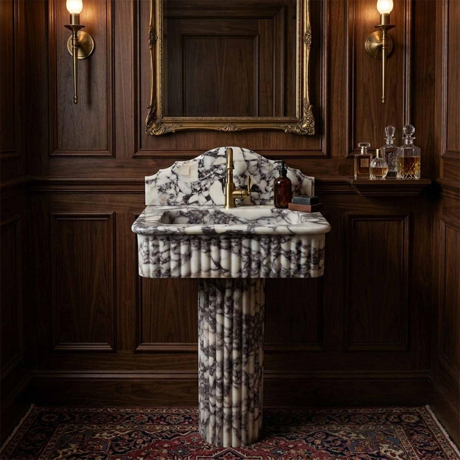 Marble pedestal sink in dark wood paneled bathroom