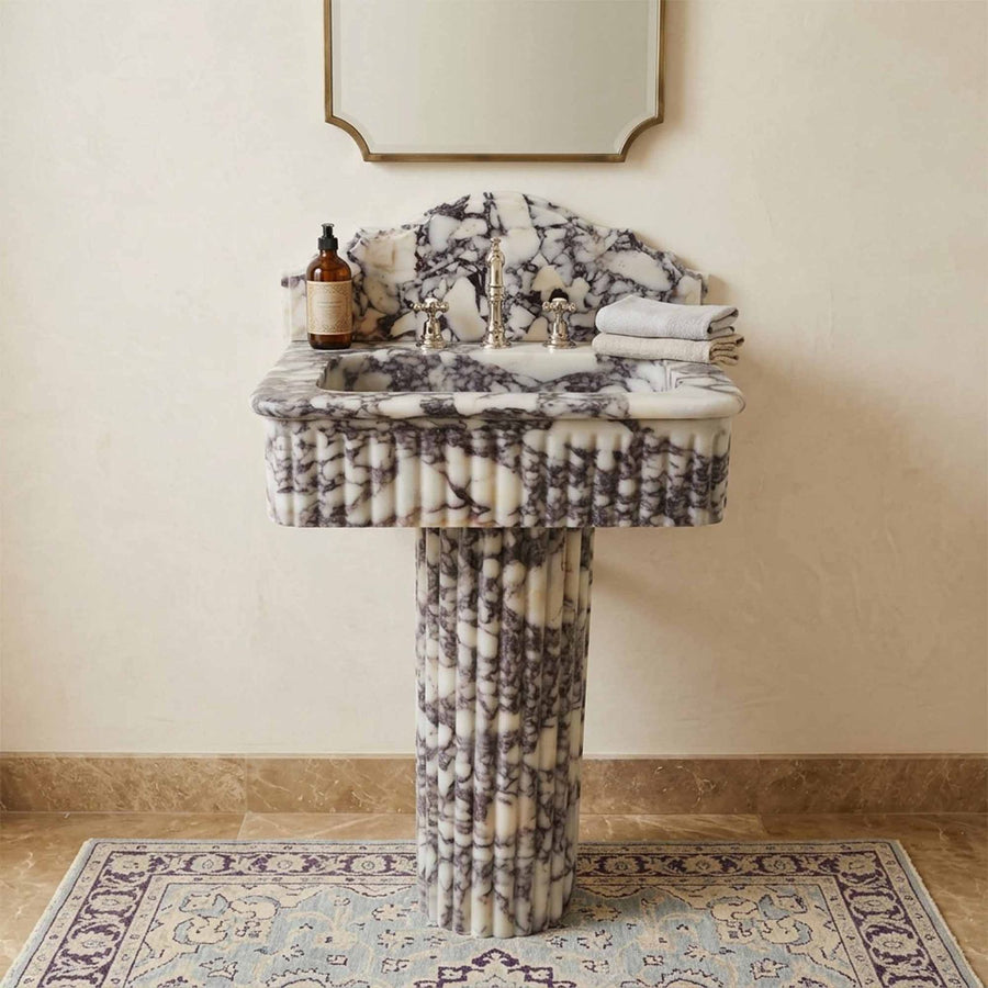 Marble pedestal sink with nickel faucet on Persian rug
