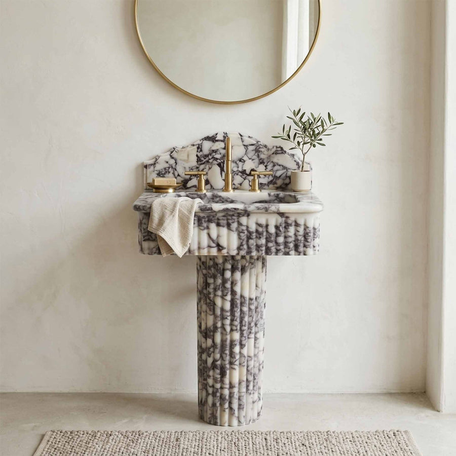 Marble pedestal sink against plaster wall in minimalist bathroom