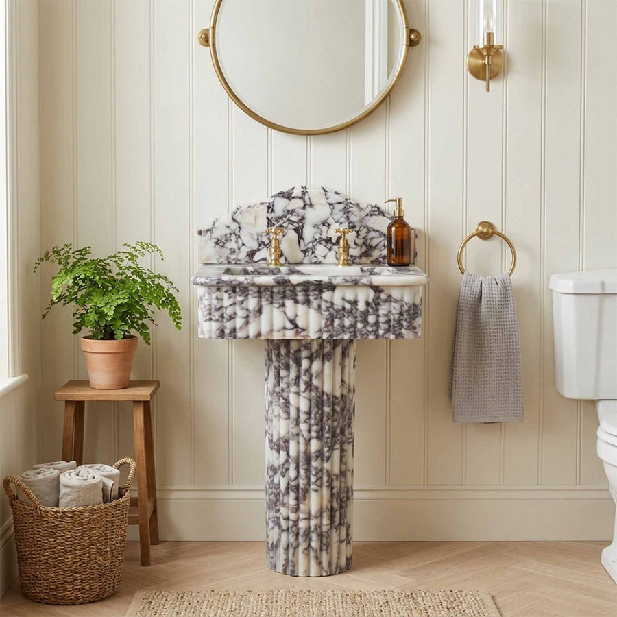Marble pedestal sink with round mirror in neutral bathroom