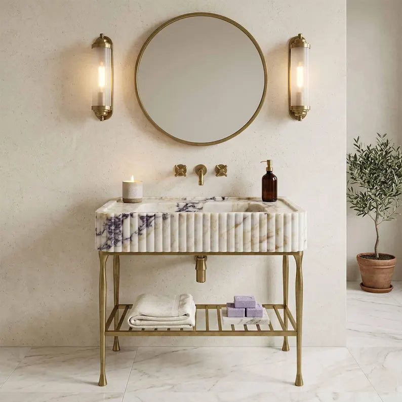 Bathroom vanity with marble sink, round mirror, and wall lights.