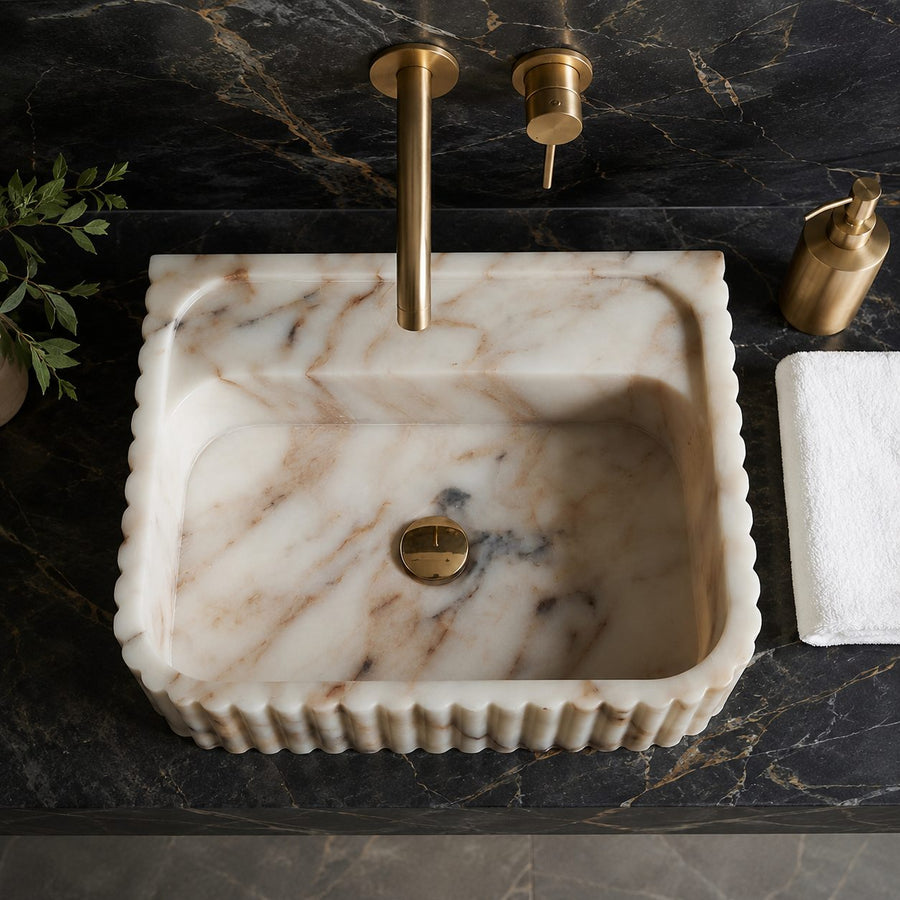 Top view of Calacatta Gold marble sink with scalloped fluted edge and brass faucet