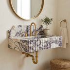 Marble sink with backsplash and exposed brass wall plumbing