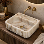 Top view of Calacatta Gold marble sink with scalloped fluted edge and brass faucet