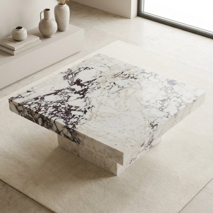 Marble coffee table in a minimalistic room with light-colored floor and walls.