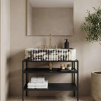 Bathroom vanity with marble countertop, black shelves, and decorative items against a beige wall.