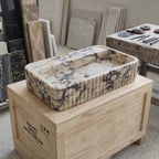 Marble sink on a wooden crate with various stone samples in the background