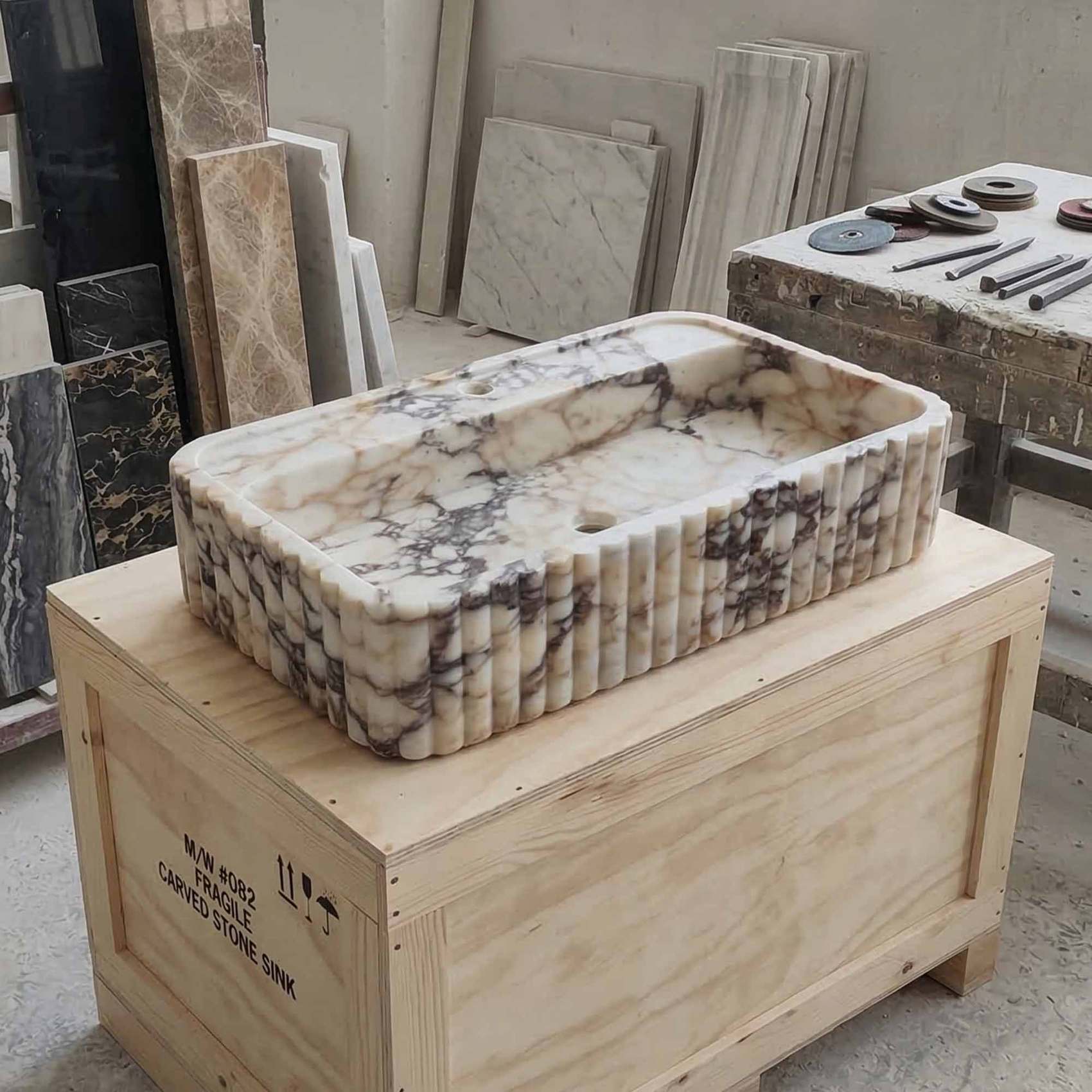 Marble sink on a wooden crate with various stone samples in the background