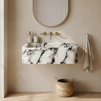 Bathroom with marble sink, gold fixtures, and a woven basket on a wooden floor.