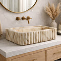 Bathroom vanity with marble sink, gold fixtures, and decorative elements.