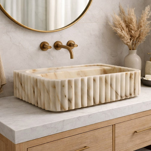 Bathroom vanity with marble sink, gold fixtures, and decorative elements.