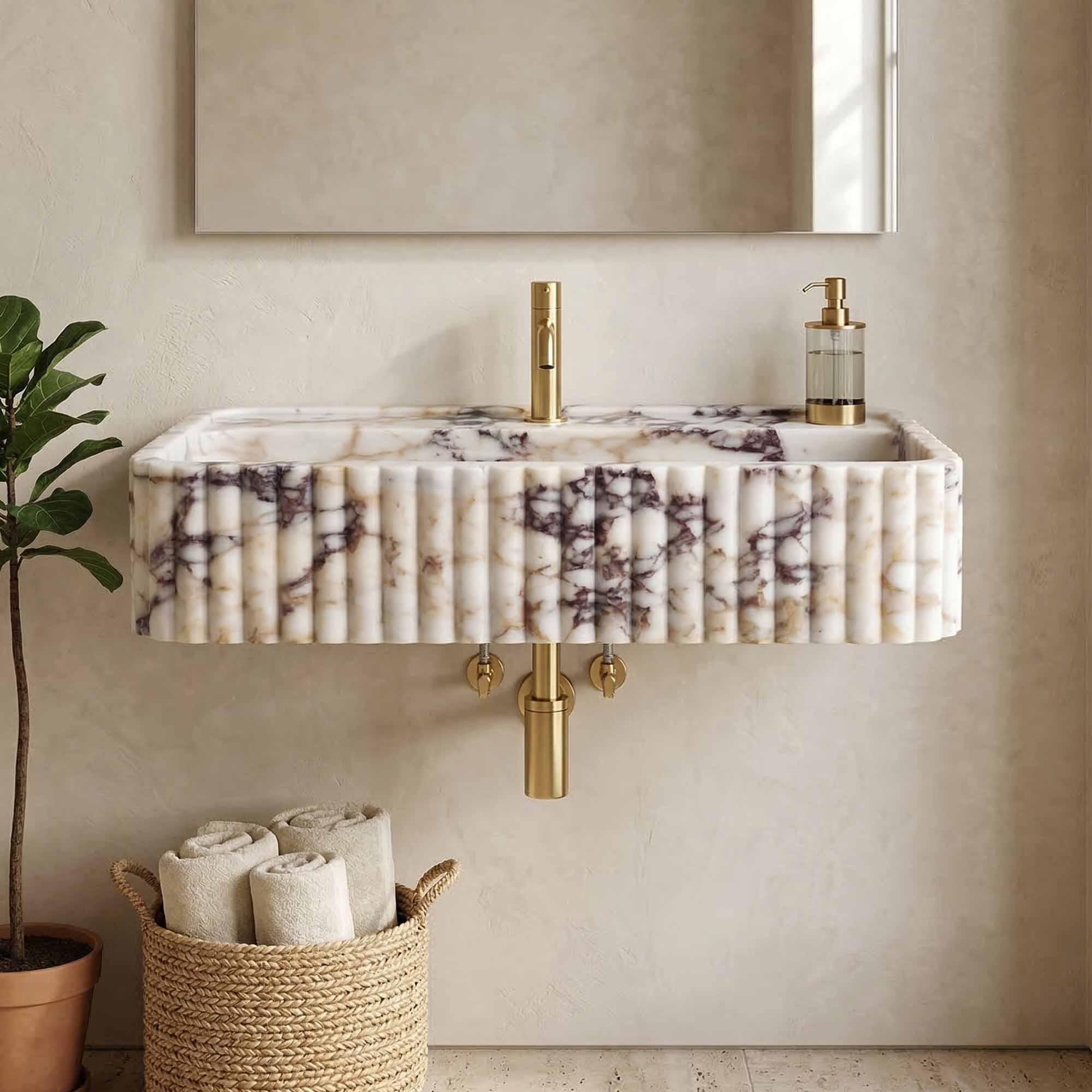 Marble-patterned sink with gold fixtures in a bathroom setting.