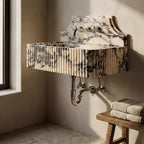 Marble-patterned wall-mounted sink with brass fixtures in a bathroom setting.