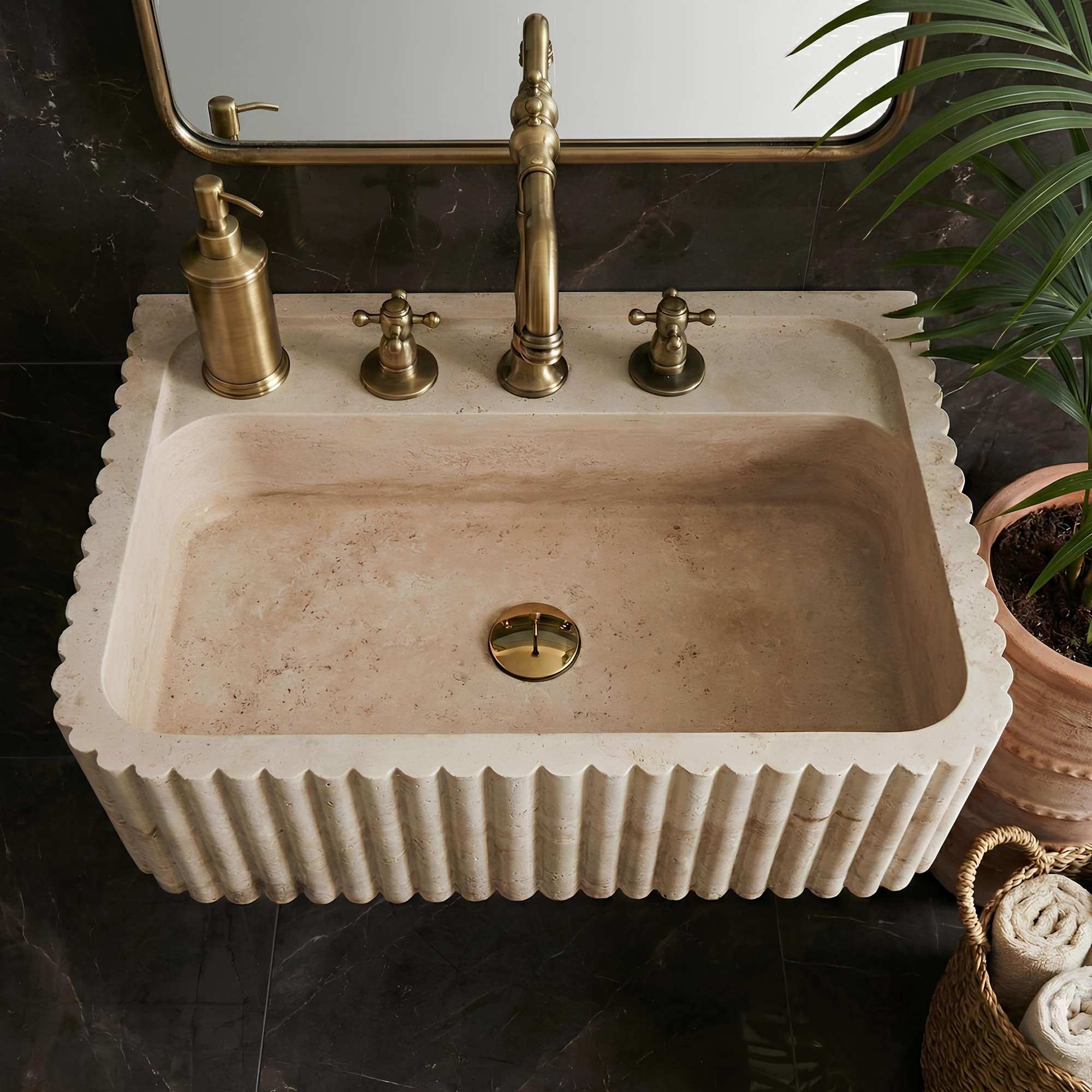 Beige stone sink with gold fixtures in a bathroom setting