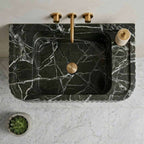 Marble sink with gold fixtures on a white countertop
