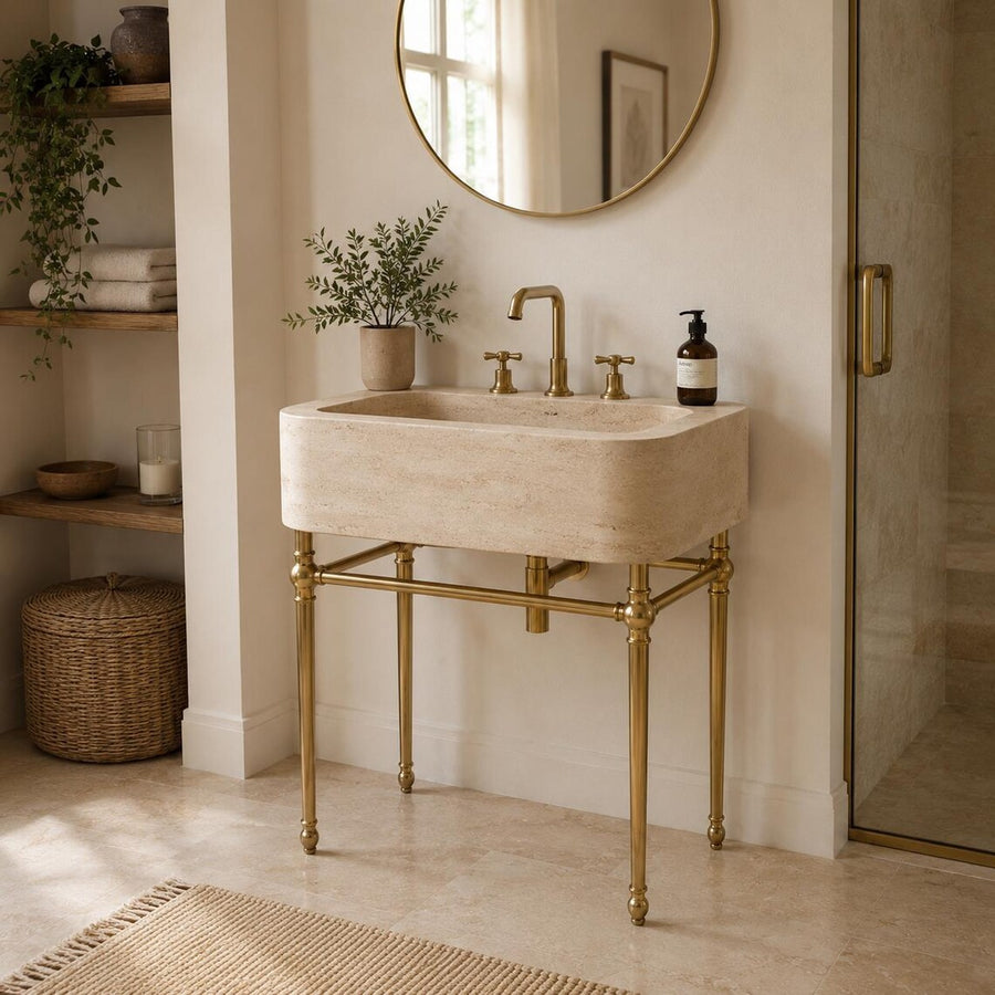 Travertine sink on brass console legs in a boho bathroom with open shelving
