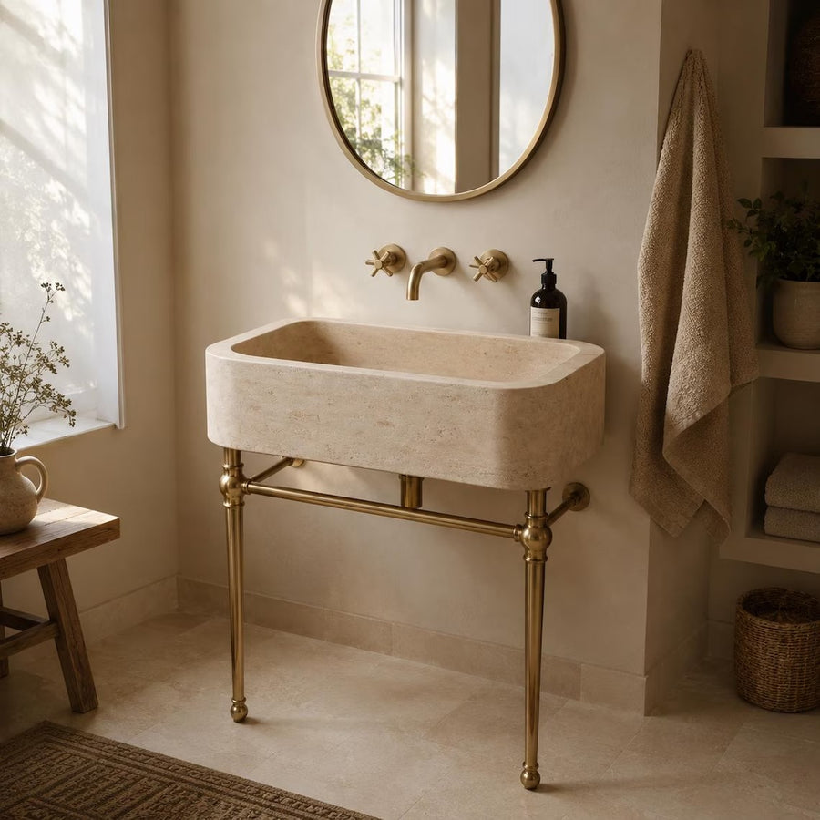Travertine sink on brass console legs in a boho bathroom with open shelving