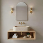 Travertine sink on a floating wood shelf under an arched mirror
