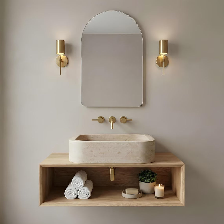 Travertine sink on a floating wood shelf under an arched mirror