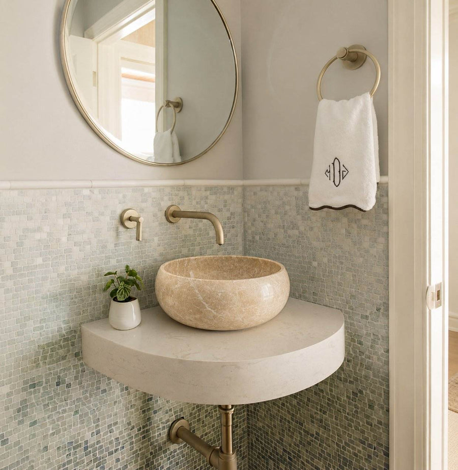 Bathroom with a stone sink, round mirror, and towel.