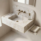 Marble sink with gold faucet and soap dispenser in a bathroom setting