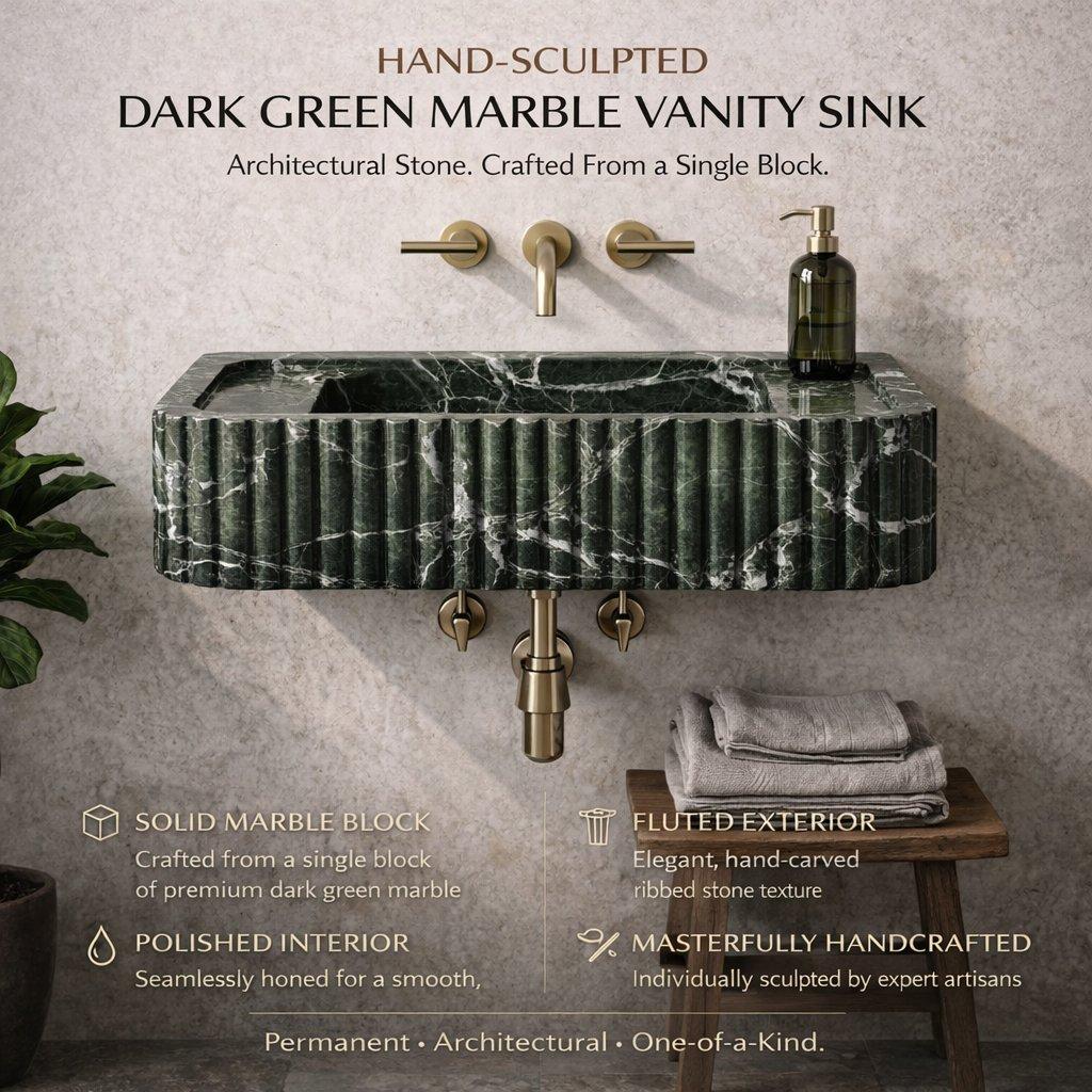 Hand-sculpted dark green marble vanity sink with gold fixtures on a gray wall.