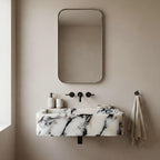 Bathroom with marble sink, mirror, and towel on beige wall